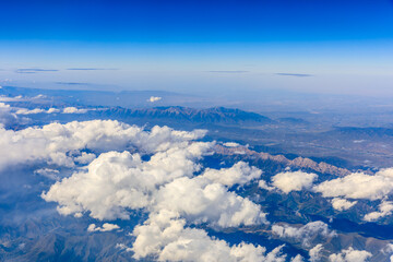 Naklejka premium Aerial view above the clouds and mountain peaks on a sunny day.mountain view from airplane.