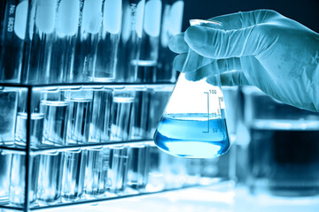 hand of scientist holding flask and pouring sample to test tube in chemical laboratory background, science laboratory research and development concept	
