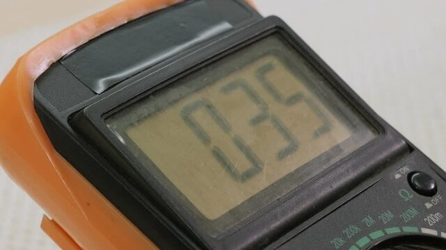 Digital multimeter and probes on a green circuit board on the table in the workshop. Close up.