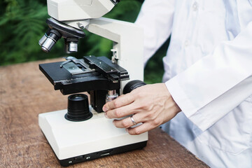 Medical healthcare biology in protective workwear sitting at the table with microscope