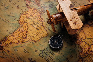 Old compass discovery and wooden plane on vintage paper antique world map background, Retro style cartography travel geography navigation, Columbus Day concept - obrazy, fototapety, plakaty