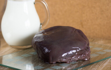 Raw pieces of liver on glass cutboard the jar with milk