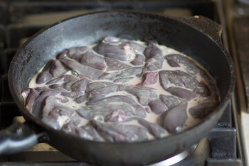 Raw cut pieces of liver and milk in the pan before cooking