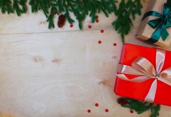 Holiday boxes with ribbons next to Christmas tree branches. 