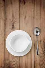 Empty white soup cup with spoon on a wooden table