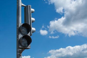 Switched off grey traffic light against bright blue cloudy sky background with copy space. Offline...