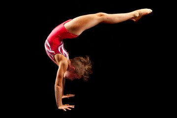 Young female gymnast on a black background