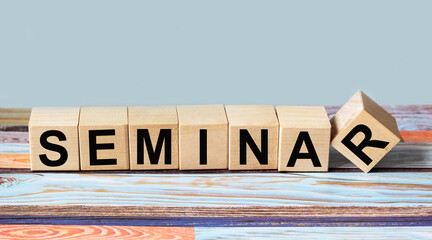 SEMINAR word written on wooden blocks in black letters, a row of blocks is located on a colored background.