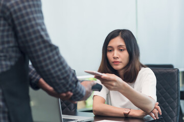 Asian woman making contactless payment to a waiter in cafe