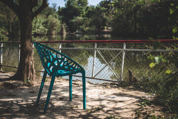 an empty chair in a park at water side
