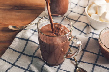 Pouring of hot cocoa drink in cup on table