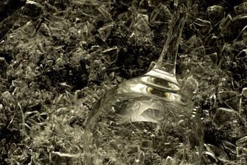An empty champagne glass merged with broken glass background. Wine glass on shards of glass in a low key.