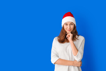 Beautiful young woman in Santa hat on color background