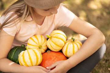 Fototapeta premium Stylish little caucasian Girl six years old Holding Freshly Harvested Pumpkin outdoor