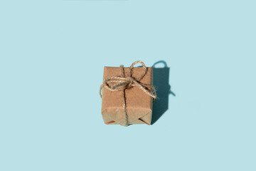 Handmade gift. Vintage parcel. Care package. Holiday present. Festive surprise. Rustic beige recycled paper box with twine bow isolated on blue copy space background.