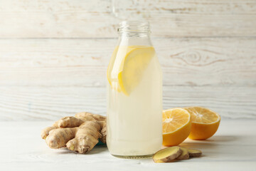 Bottle of ginger lemon water on white wooden background