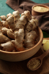 Board with fresh ginger on green background