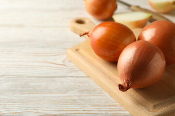 Board with onion and knife on wooden background