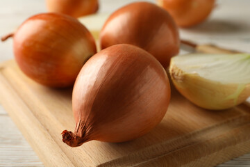 Board with onion on wooden background, close up