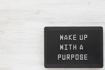 'Wake up with a purpose' words on a black lightbox on a white wooden surface, top view. From above,...