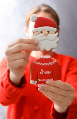 Woman holding delicious homemade Christmas cookies on grey background, closeup