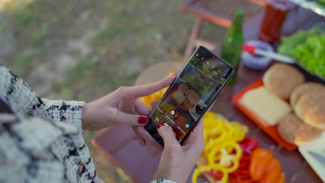 Woman hands taking pictures of the picnic food with the phone. Close-up.