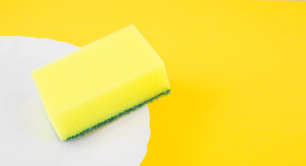 Yellow sponge on the plate. Cleaning and housewashing concept.