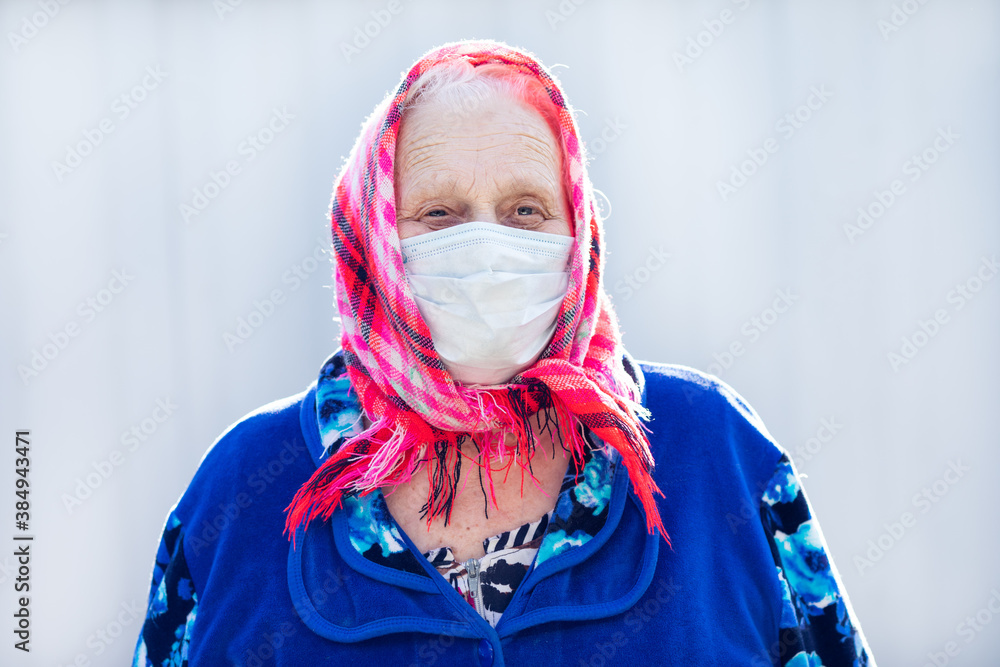 Wall mural Portrait of an old grandmother in a protective mask. The problem of the coronavirus pandemic.