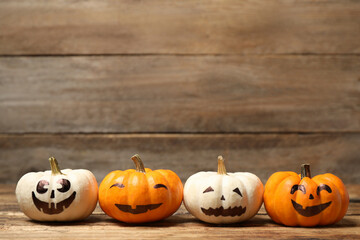 Pumpkins with scary faces on wooden background, space for text. Halloween decor