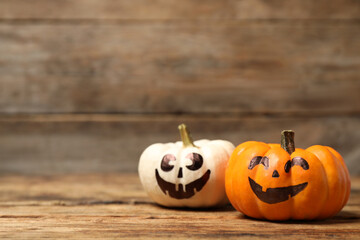 Pumpkins with scary faces on wooden background, space for text. Halloween decor