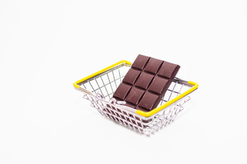 a small grocery basket contains sweets (chocolate and iced candies) on a white background. space for text