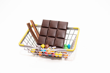 a small grocery basket contains sweets (chocolate and iced candies) on a white background. space for text
