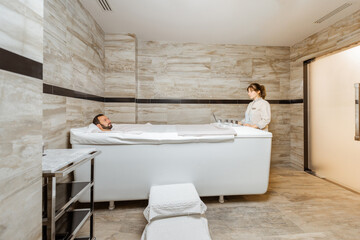 Man relaxing during a medical treatment at the bath filled with carbon dioxide at balneology room...