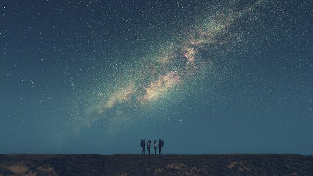 The four friends standing on the mountain top on the starry sky background