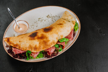 Tasty sandvich with salami and salad on wooden background