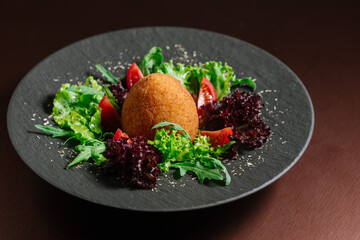 Oval cutlet with vegetables and salad on wooden background