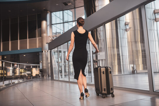 Elegant woman walking through the airport with a suitcase