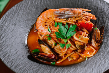 A dish of pasta with vegetables and big king shrimp