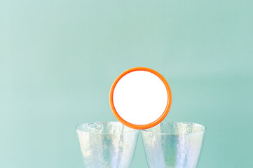 round jar with white space for text on mother of pearl wine glasses on pastel blue clear background