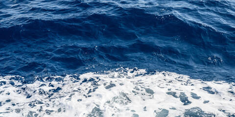 Panorama of background blue sea with small waves and white foam, copy space for text