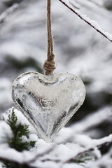 Christmas and New Year holidays season.Valentine's day. silver metal heart on a twig in a snowy...