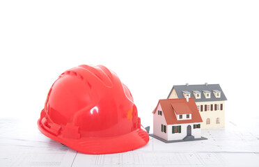 Red hard hat and two small house models on drawings