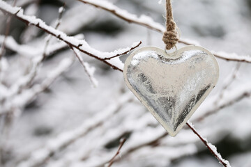 Christmas and New Year .Valentine's day concept. silver metal heart on a twig in a snowy...