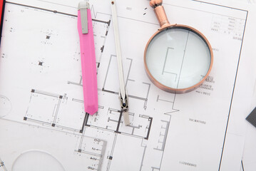 Magnifying glass and wallpaper knife on space plan drawings