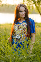 Wild girl in the grass, passionately looks to the side. She is wearing a blue T-shirt with a painted lion.