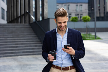 Handsome office worker holding smartphone and smiling. Happy young man using mobile phone apps,...