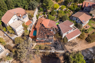Forest fire damage to local houses, with burnt trees and house, Aerial view.