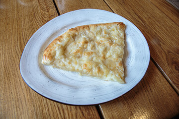Large piece of pizza with cheese. Hot tortilla with cheese, Khachapuri, Caucasian kitchen.