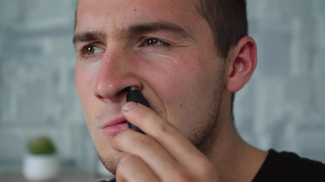 a man shaves his nose hair with a special trimer