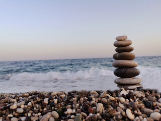 The art of balance made of stones on the beach. Mediterranean in the background.